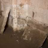 Esploriamo il vano completamente spoglio, camminando su una superficie resa scivolosa dalla fanghiglia. La pavimentazione originaria � stata infatti trafugata, al pari dell'acquasantiera un tempo posizionata sulla sinistra dell'accesso. Addossate sui muri notiamo qua e l� delle lastre di pietra scampate alle attenzioni dei ladri